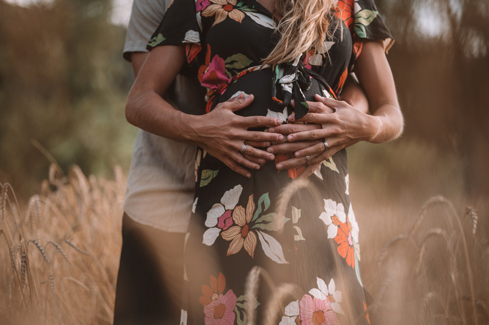 mains posées sur le ventre rond d'une femme enceinte – lumière dorée