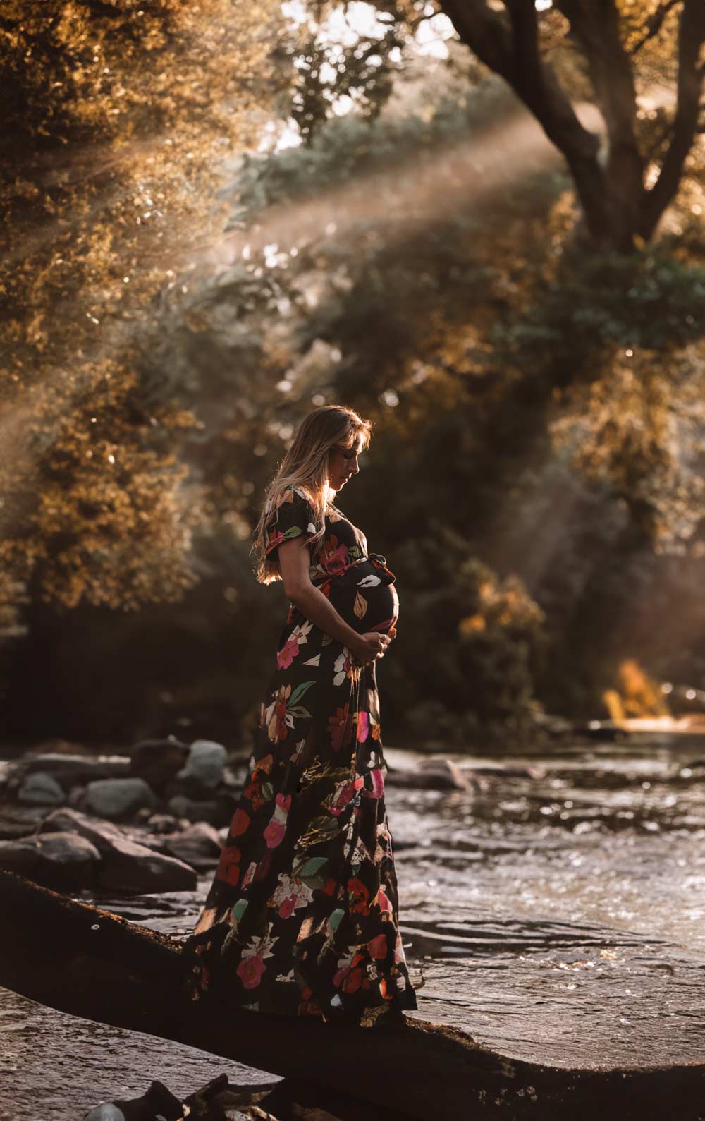 femme enceinte debout au bord d’une rivière au coucher du soleil